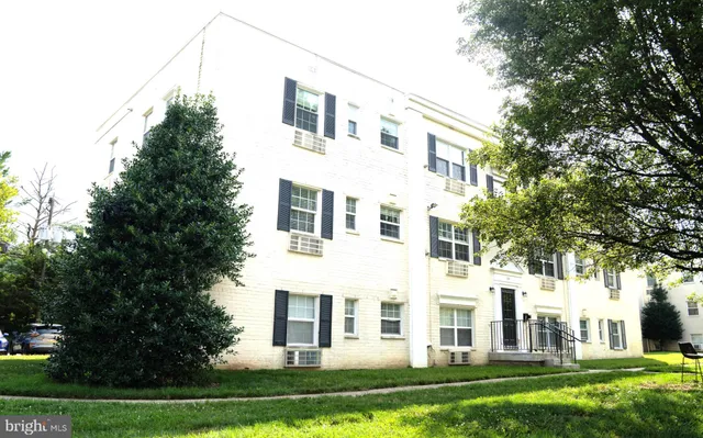 a view of a white house next to a yard with big trees
