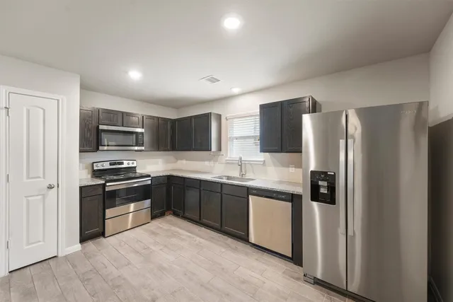 a modern kitchen with stainless steel appliances granite countertop a refrigerator and a stove top oven