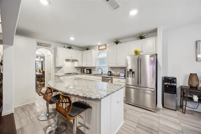 a kitchen with stainless steel appliances granite countertop a refrigerator a stove a sink dishwasher and a refrigerator with wooden floor