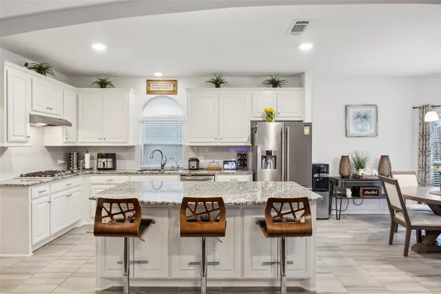 a kitchen with stainless steel appliances granite countertop a table and chairs in it