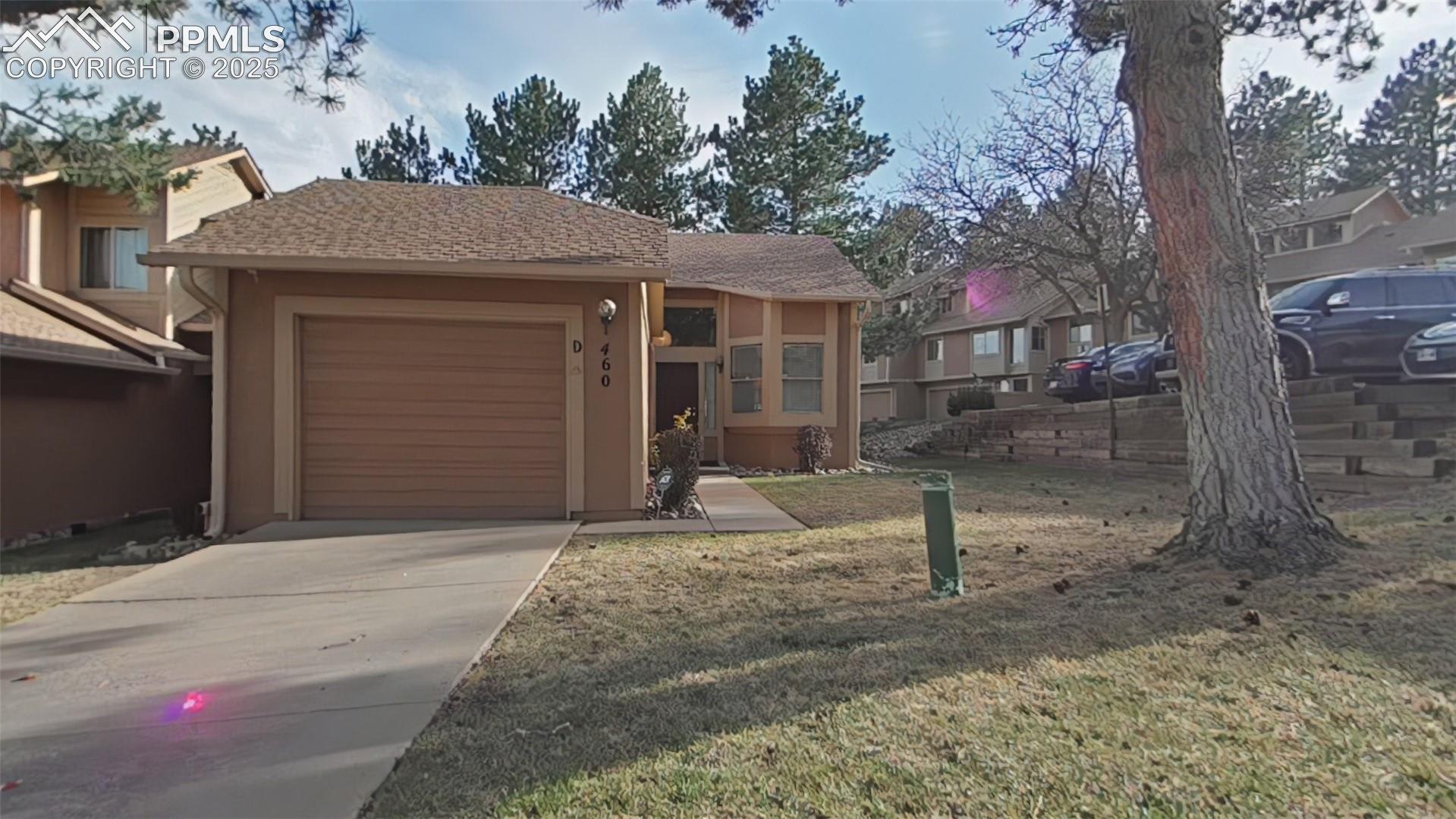 460 Autumn Ridge Circle, Unit D Colorado Springs, CO 80906 - Photo 1 of 38 View of front of property featuring stucco siding, concrete driveway, a front yard, and an attached garage
