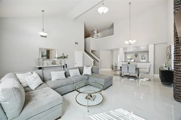 a living room with furniture kitchen view and a chandelier