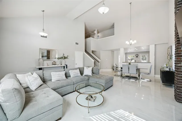 a living room with furniture kitchen view and a chandelier