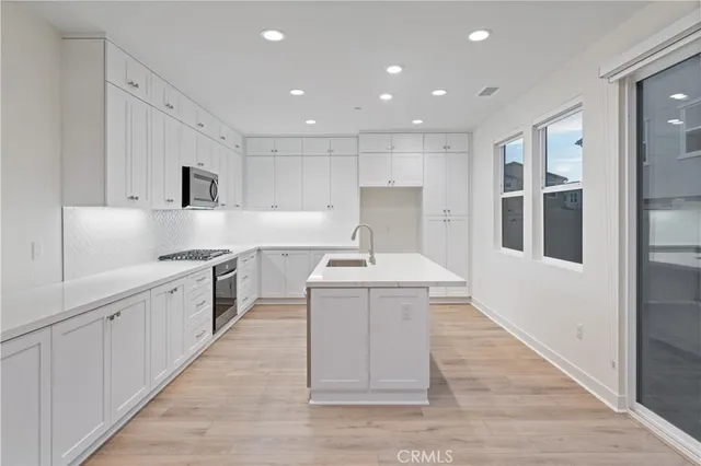 a large white kitchen with wooden floors and stainless steel appliances
