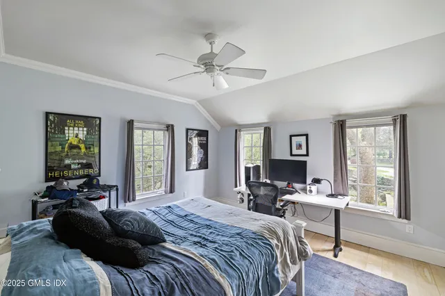 a bedroom with a bed couch and windows