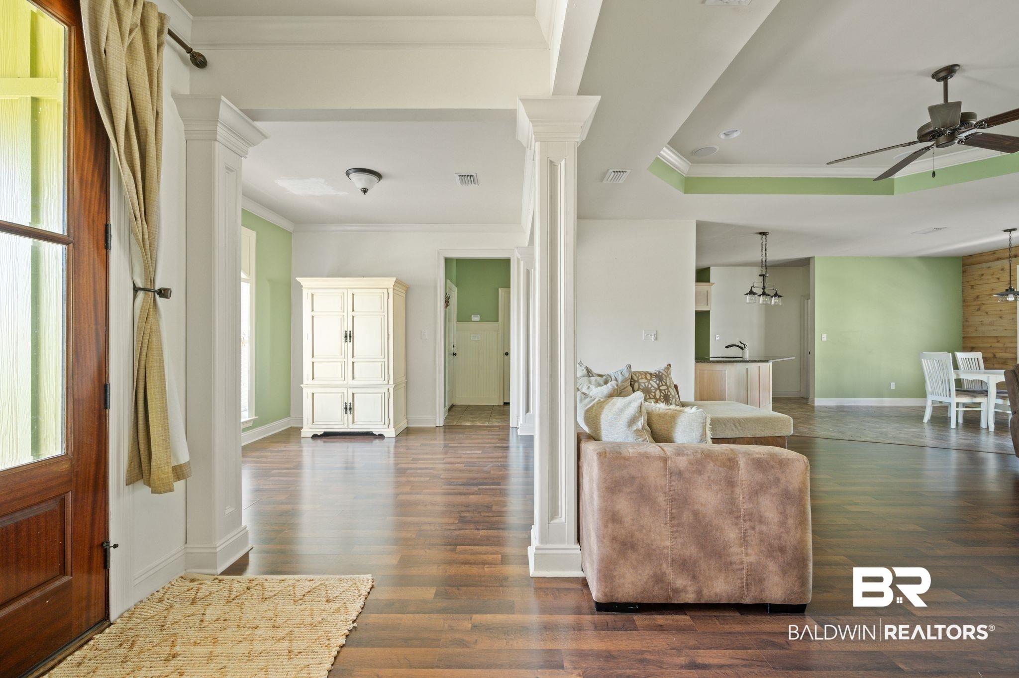 3879 Symphony Way West Semmes, AL 36575 - Photo 29 of 34 Living room with ceiling fan, a raised ceiling, ornate columns, and dark hardwood / wood-style flooring