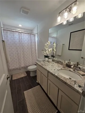 a bathroom with a granite countertop sink a toilet a mirror and shower