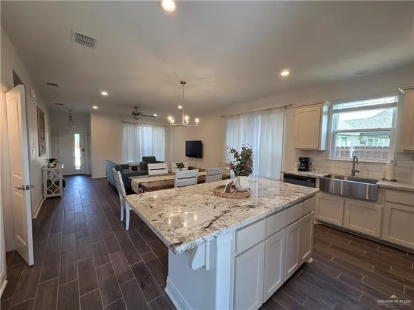 a large kitchen with kitchen island a stove a sink dishwasher and a dining table with wooden floor