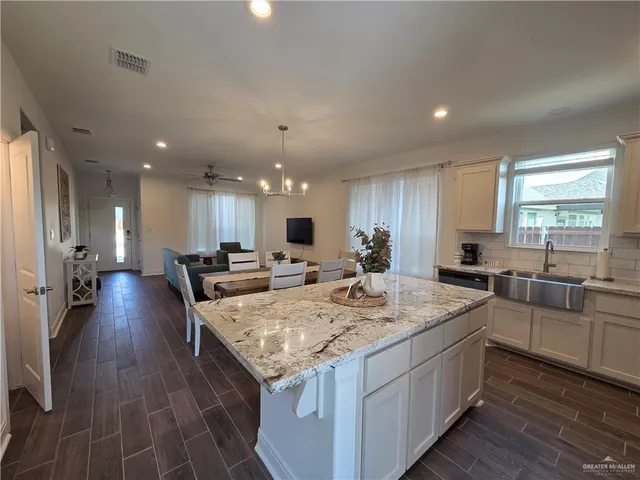 a large kitchen with kitchen island a stove a sink dishwasher and a dining table with wooden floor