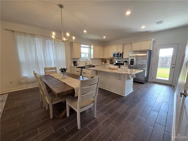 a kitchen with a dining table chairs and wooden floor