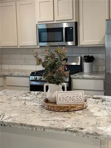 a view of kitchen with stainless steel appliances granite countertop stove top oven and cabinets