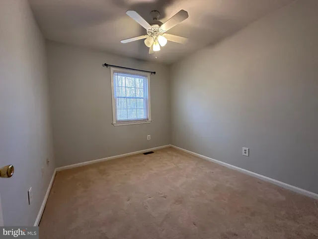 an empty room with a chandelier fan and windows