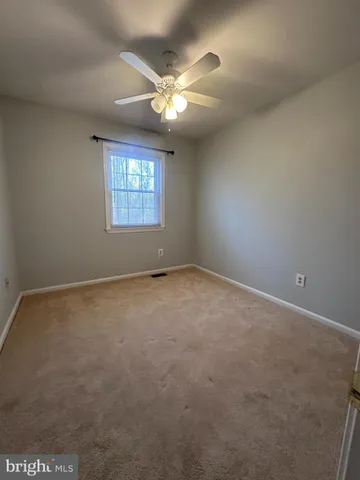 an empty room with a ceiling fan and window