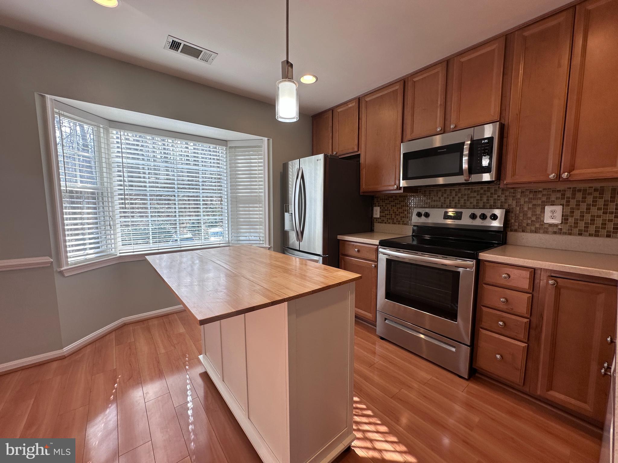 5832 1st Landing Way, Unit 137 Burke, VA 22015 - Photo 3 of 30 a kitchen with stainless steel appliances kitchen island granite countertop a stove a sink and a microwave