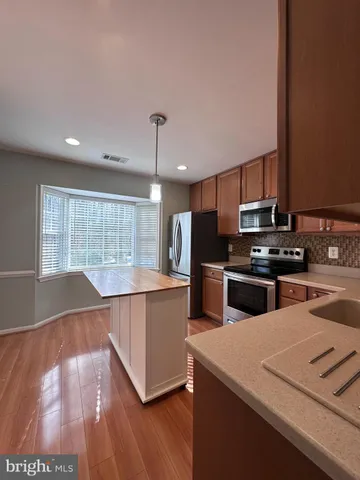 a kitchen with stainless steel appliances wooden floor sink and wooden cabinets