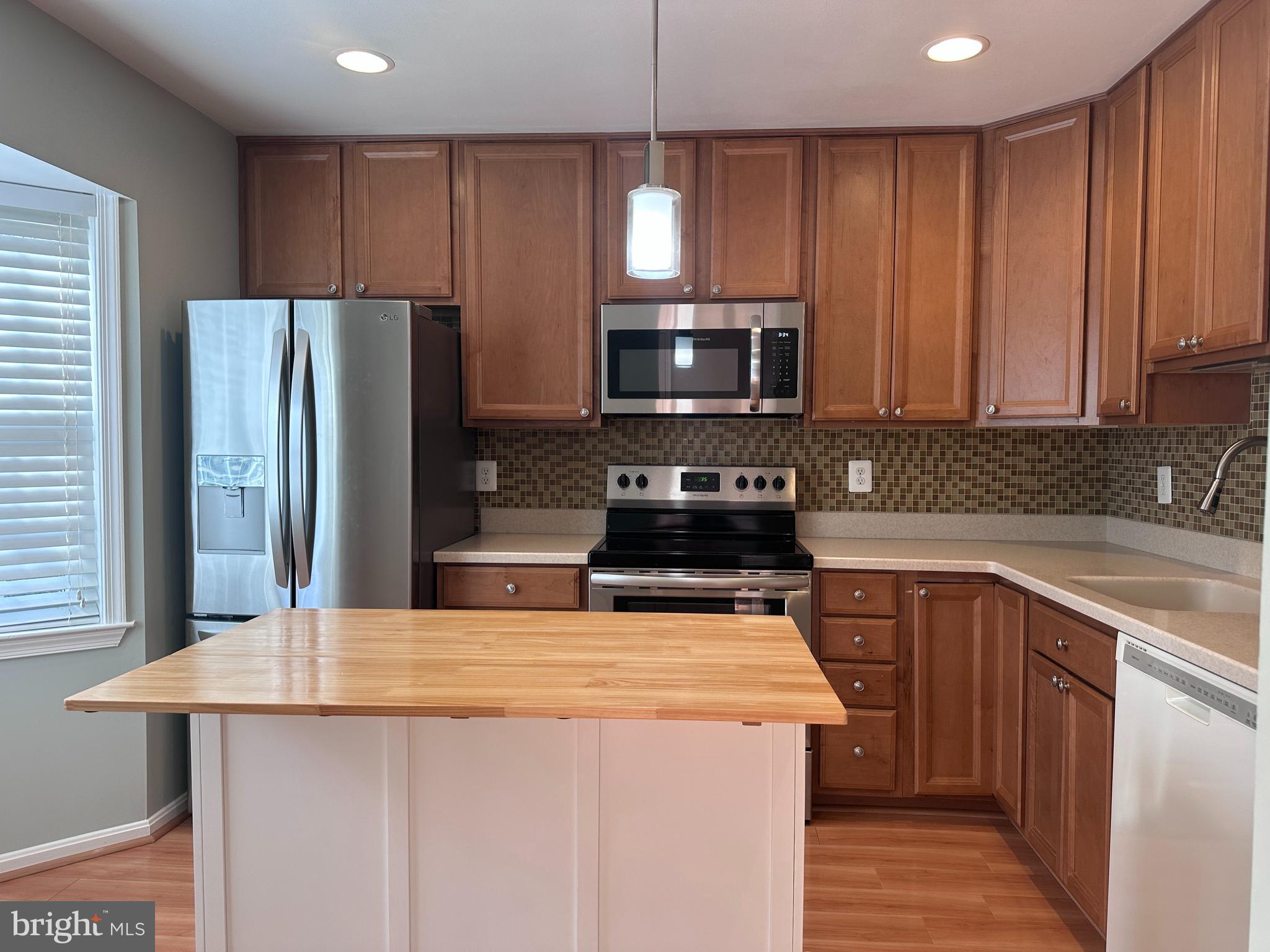 5832 1st Landing Way, Unit 137 Burke, VA 22015 - Photo 6 of 30 a kitchen with kitchen island granite countertop stainless steel appliances a sink a stove a refrigerator cabinets and a window
