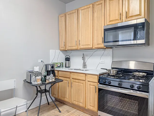 a kitchen with stainless steel appliances granite countertop a stove a sink and a microwave