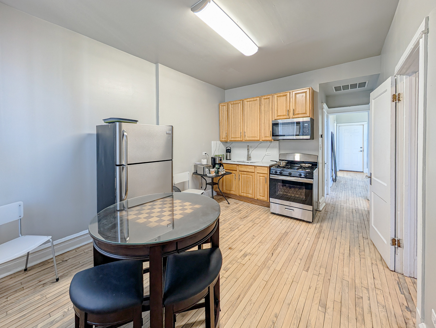 2838 West Roosevelt Road, Unit 3R Chicago, IL 60612 - Photo 5 of 23 a kitchen with stainless steel appliances granite countertop a stove a refrigerator a sink a dining table and chairs with wooden floor