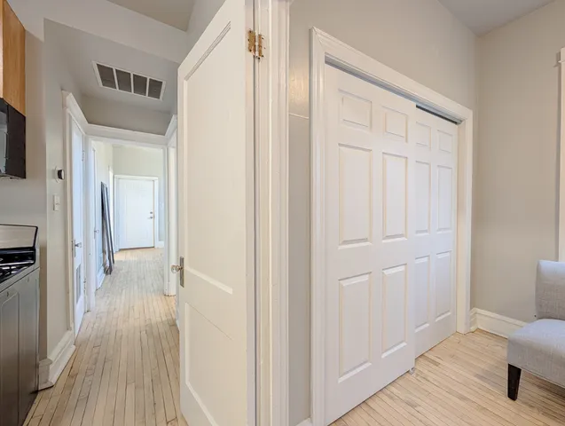 a view of a hallway with wooden floor and closet area