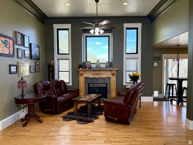 202 375 West Providence, UT 84332 - Photo 6 of 61 Elegant living area featuring a handcrafted mantle over a gas fireplace, high ceiling and windows, light wood-style floors, crown molding, and a ceiling fan