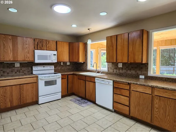 a kitchen with granite countertop cabinets stainless steel appliances a sink and a large window