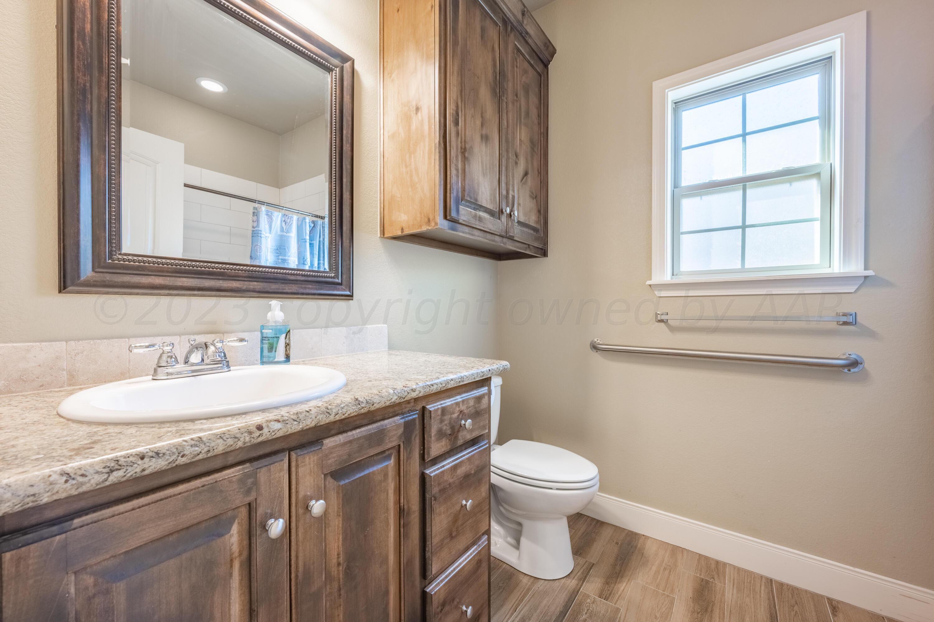 4910 Hicks Street Amarillo, TX 79118 - Photo 16 of 19 a bathroom with a granite countertop toilet sink and mirror