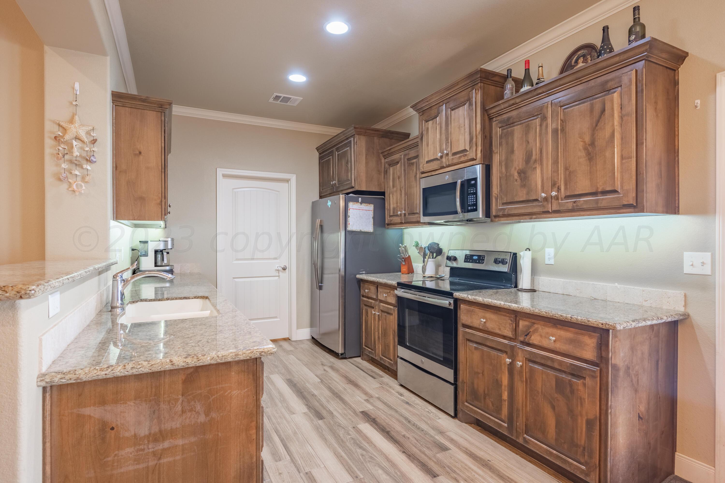 4910 Hicks Street Amarillo, TX 79118 - Photo 5 of 19 a kitchen with granite countertop a sink stove and refrigerator