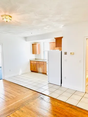 a view of a livingroom with wooden floor and a refrigerator