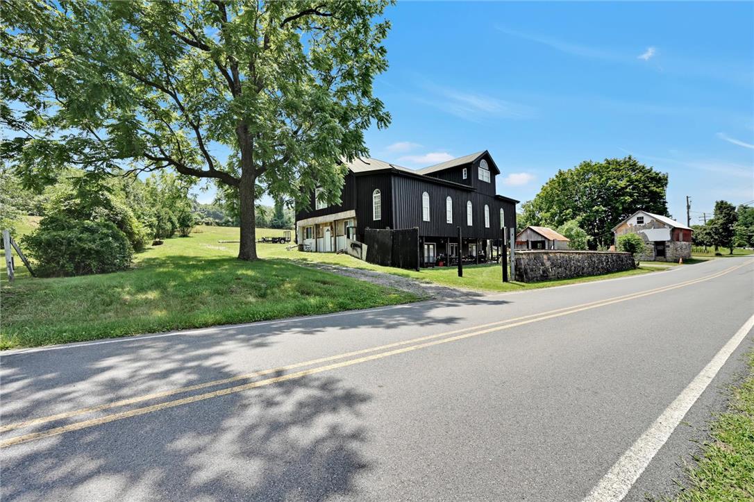101 Conrad Road Fleetwood, PA 19522 - Photo 2 of 42 A picturesque rural property boasts a charming black structure nestled beside a verdant lawn, fronting a quiet road.