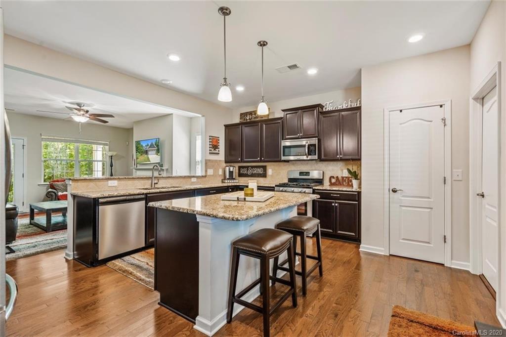 4303 Perth Road Indian Land, SC 29707 - Photo 13 of 32 a kitchen with kitchen island granite countertop wooden floors and stainless steel appliances