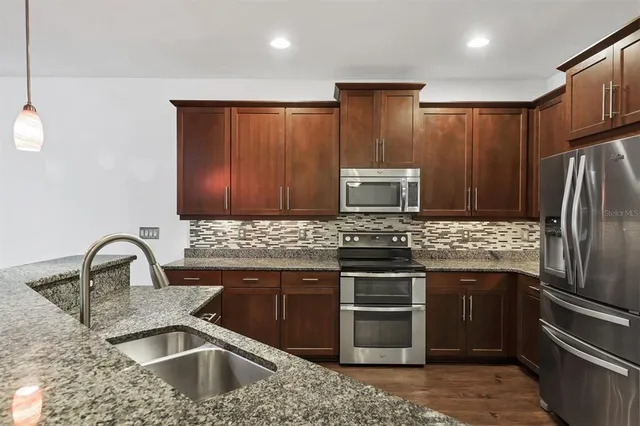 a kitchen with kitchen island stainless steel appliances a sink stove and refrigerator