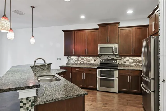 a kitchen with granite countertop stainless steel appliances and wooden cabinets
