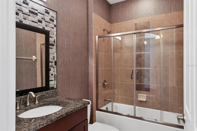 a bathroom with a granite countertop sink a mirror and shower