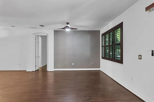 a view of an empty room with wooden floor and a window
