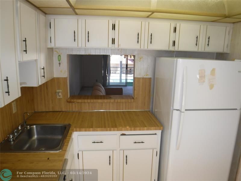 a kitchen with white cabinets and refrigerator