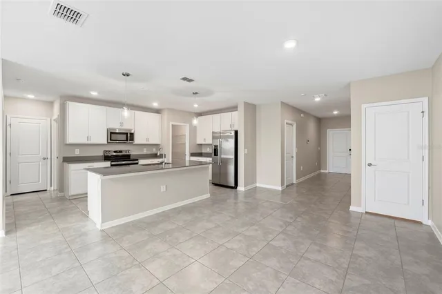 a large white kitchen with stainless steel appliances granite countertop a large counter top and a stove top oven