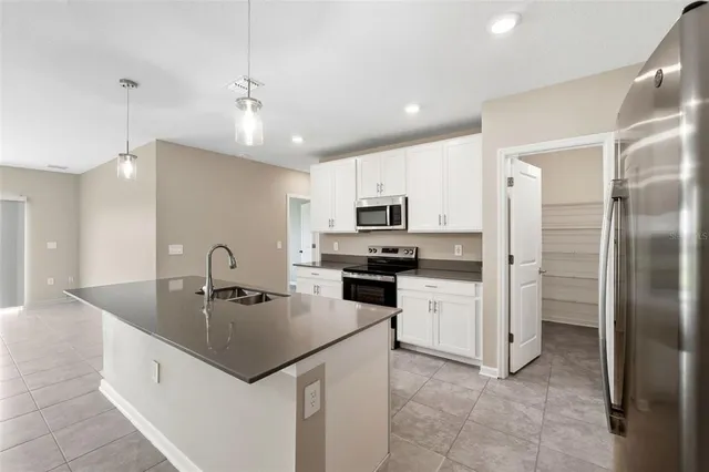 a kitchen with a refrigerator a sink cabinets and wooden floor