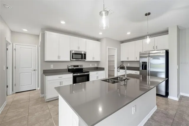 a large kitchen with stainless steel appliances granite countertop a sink a stove and refrigerator
