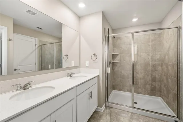 a bathroom with a double vanity sink mirror and shower