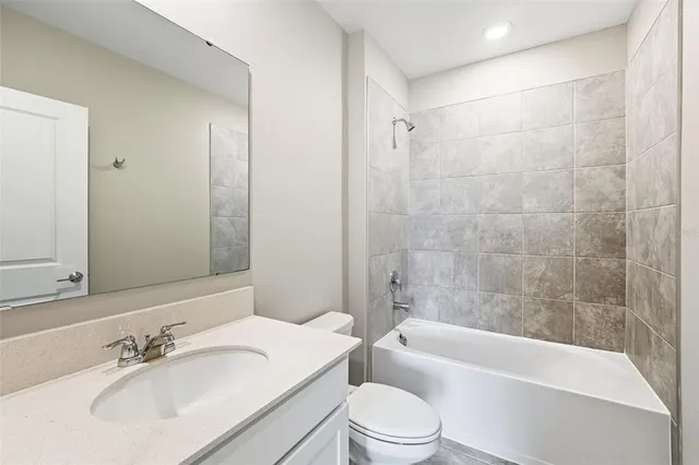 a bathroom with a bathtub shower sink vanity mirror and toilet