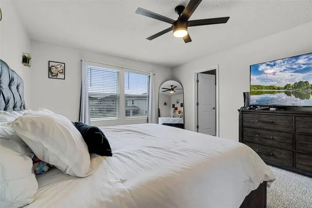a bedroom with a bed and a flat tv screen on dresser