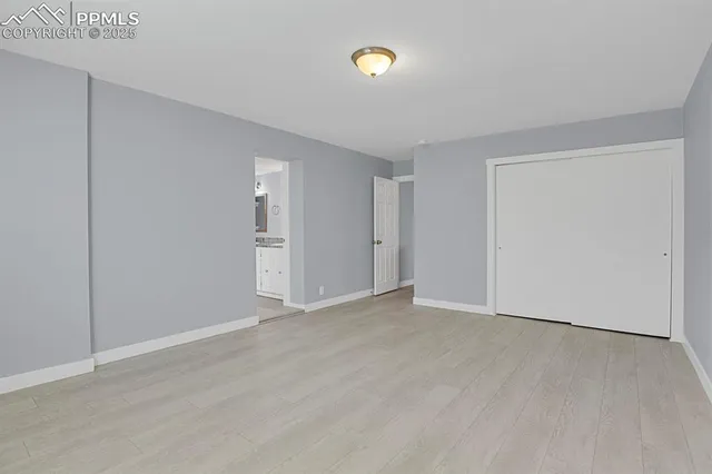 a view of an empty room with wooden floor and closet