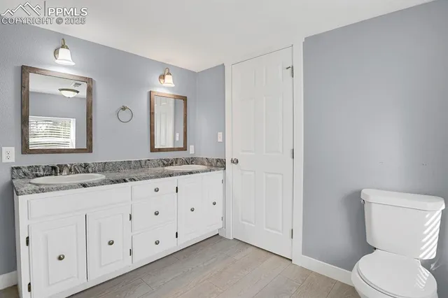 a bathroom with a granite countertop toilet sink and mirror