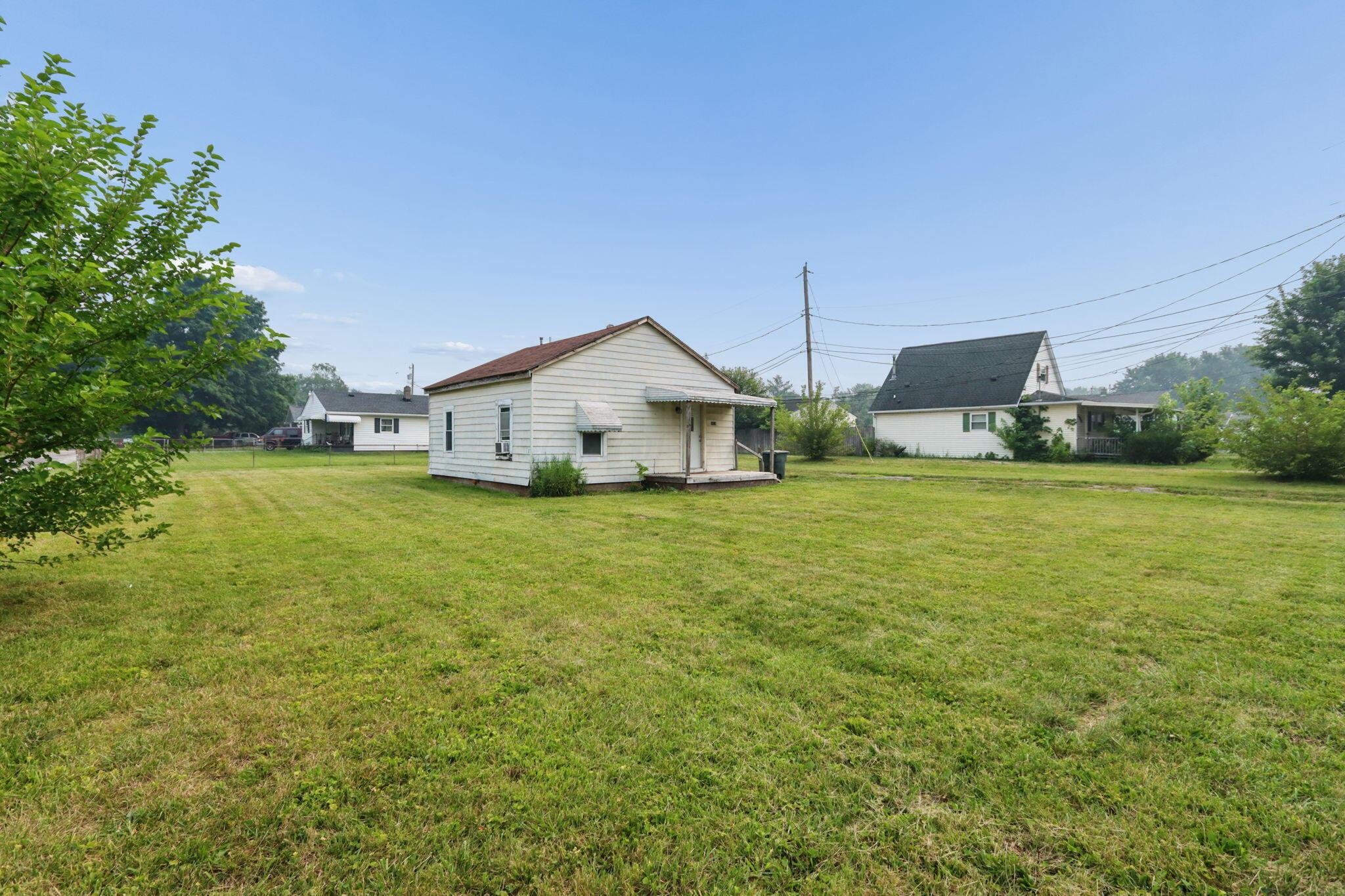 1128 Hilock Road Columbus, OH 43207 - Photo 27 of 29 Expansive grassy yard area with a mature tree to the left and a single-story residence featuring white siding and a brown roof