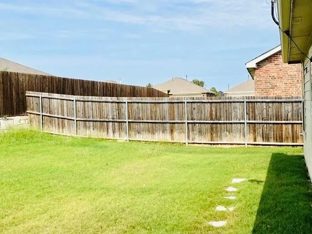 a view of a garden with a small yard and a wooden fence