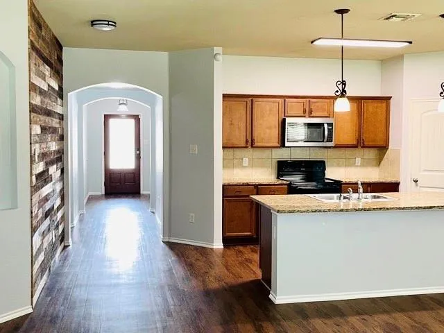 a kitchen with stainless steel appliances granite countertop a refrigerator a stove top oven a sink and dishwasher