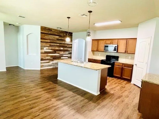 a kitchen with stainless steel appliances granite countertop a stove a sink and a wooden floors