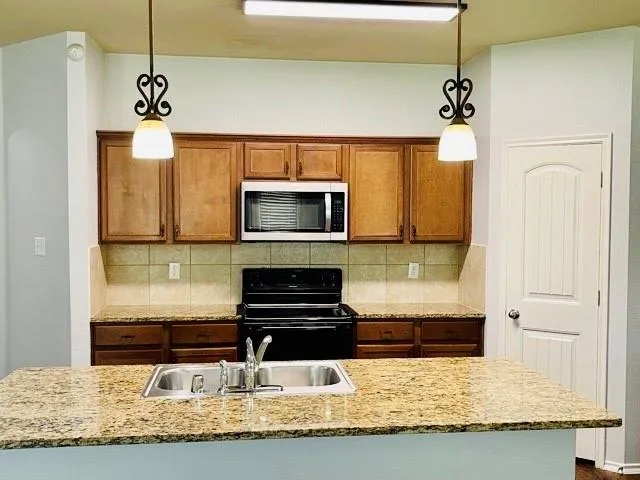 a kitchen with kitchen island granite countertop a sink stainless steel appliances a counter top space and cabinets