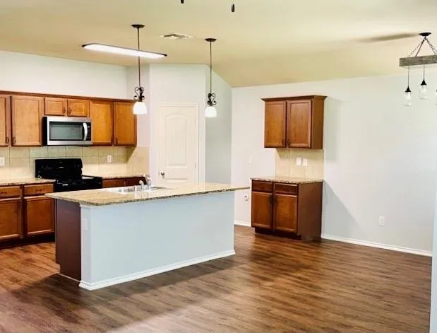 a large kitchen with stainless steel appliances granite countertop a stove a sink and a microwave