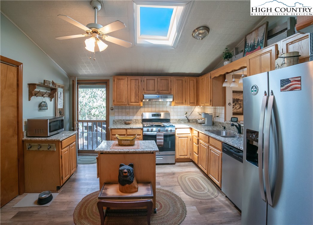 10 Locust Road Newland, NC 28657 - Photo 15 of 36 a kitchen with stainless steel appliances granite countertop a refrigerator a stove a sink dishwasher a dining table and chairs with wooden floor